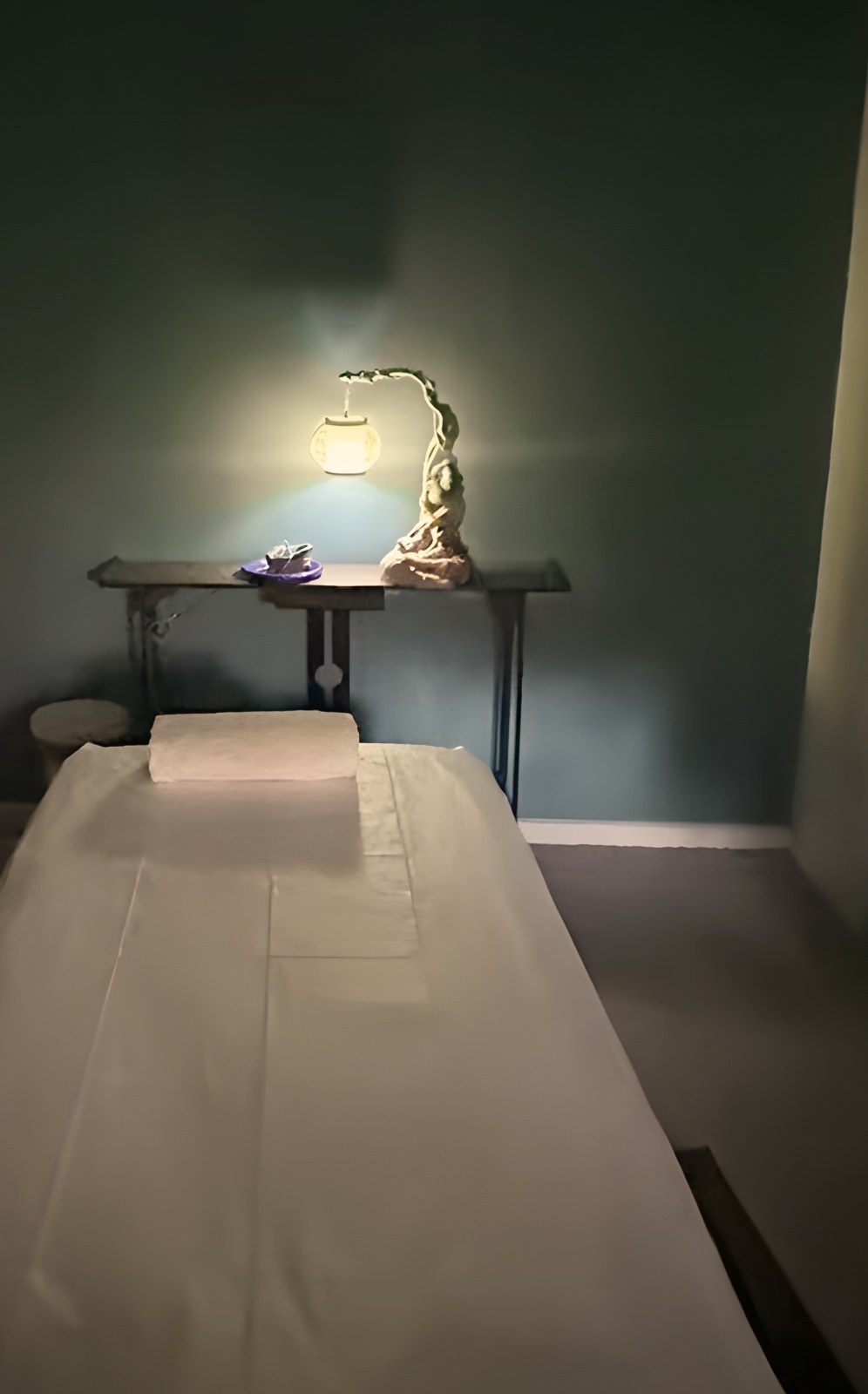 Massage room 2: blue wall and a sculpted lamp above the massage table